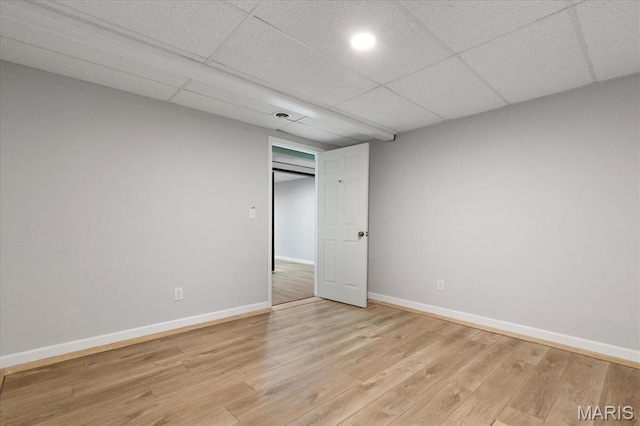 unfurnished bedroom with light wood-type flooring, baseboards, and a paneled ceiling