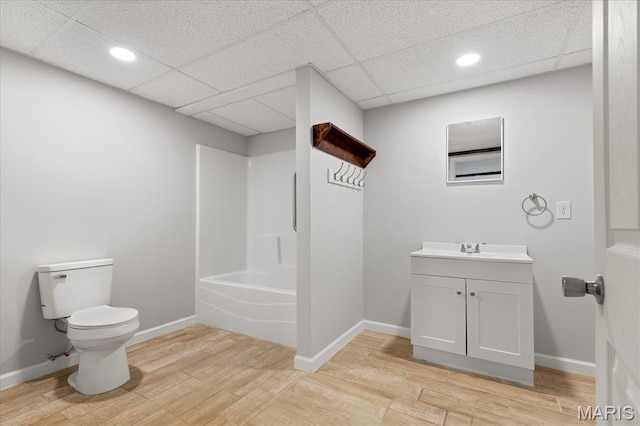 bathroom with toilet, wood finished floors, vanity, baseboards, and recessed lighting