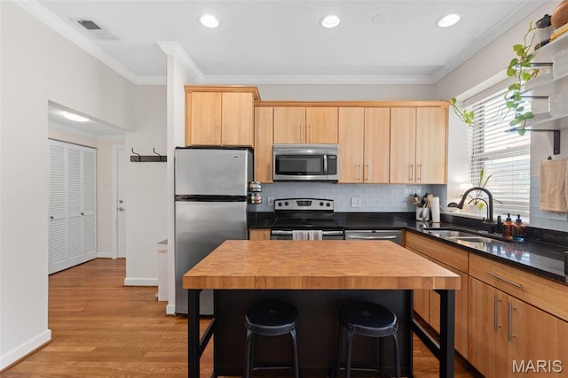5621 Pershing Ave Unit 21, Saint Louis, MO 63112 - kitchen featuring appliances with stainless steel finishes, a sink, wooden counters, a kitchen bar, and crown molding