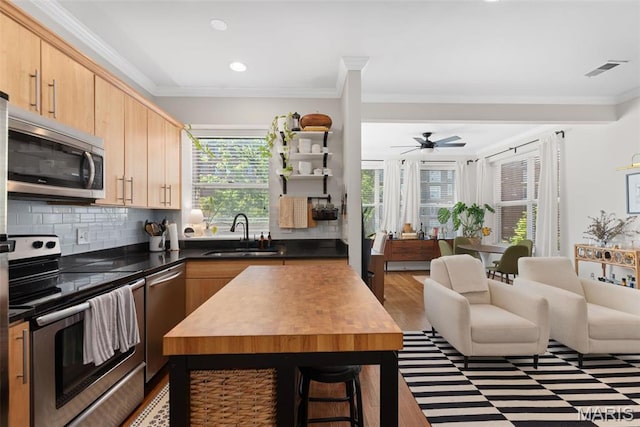 5621 Pershing Ave Unit 21, Saint Louis, MO 63112 - kitchen featuring appliances with stainless steel finishes, a sink, crown molding, backsplash, and recessed lighting