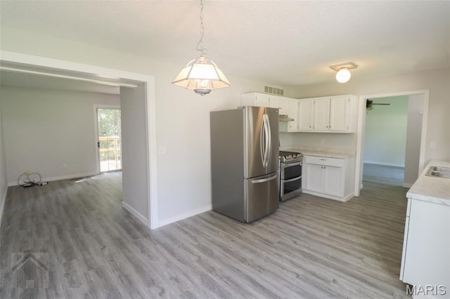 104 Wild Rose Pl, Saint Robert, MO 65584 - kitchen with stainless steel appliances, light countertops, light wood-style floors, white cabinetry, and hanging light fixtures