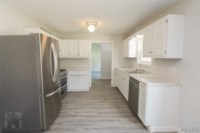 104 Wild Rose Pl, Saint Robert, MO 65584 - kitchen featuring appliances with stainless steel finishes, light countertops, light wood-type flooring, and white cabinets
