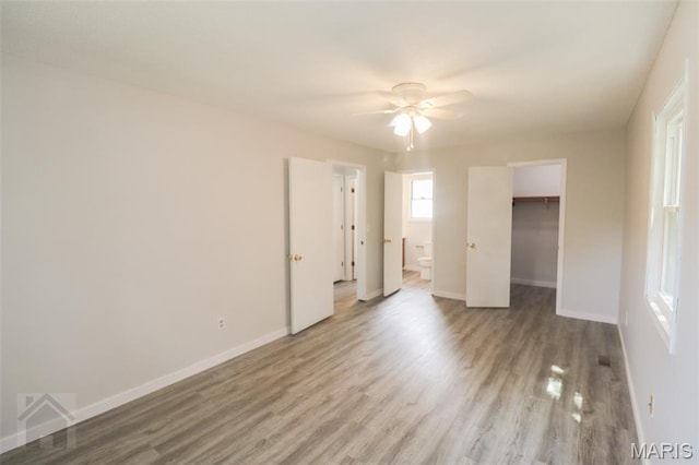 104 Wild Rose Pl, Saint Robert, MO 65584 - unfurnished bedroom featuring wood finished floors, a walk in closet, ensuite bathroom, and ceiling fan