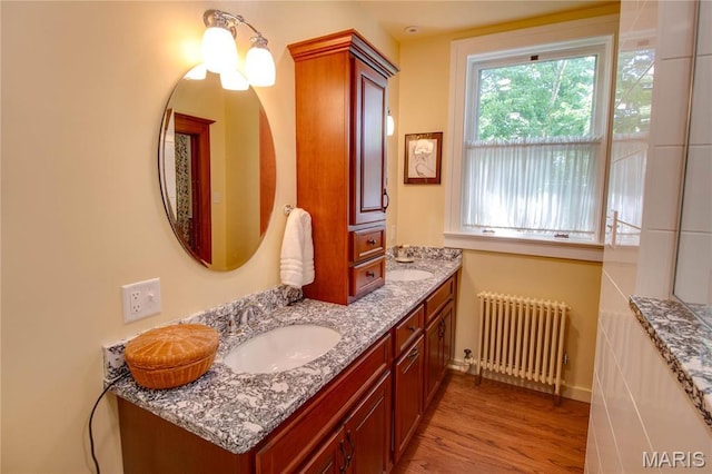 619 E Main St, Carlinville, IL 62626 - bathroom featuring radiator heating unit, wood finished floors, double vanity, and baseboards