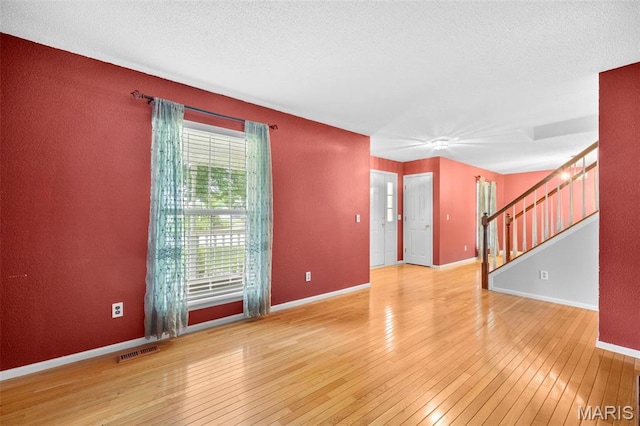 14 Sunderland Ct, Saint Charles, MO 63303 - unfurnished room featuring wood-type flooring, stairway, baseboards, and a textured ceiling