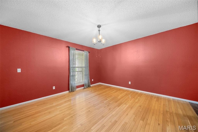 14 Sunderland Ct, Saint Charles, MO 63303 - unfurnished room featuring a chandelier, light wood-type flooring, baseboards, a textured wall, and a textured ceiling