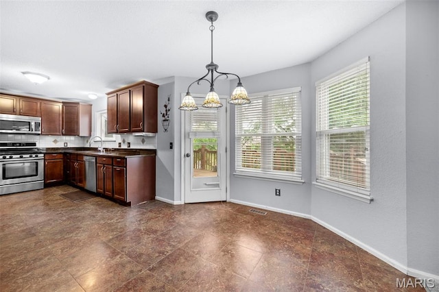 14 Sunderland Ct, Saint Charles, MO 63303 - kitchen featuring appliances with stainless steel finishes, dark countertops, baseboards, decorative light fixtures, and a chandelier