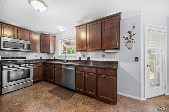 14 Sunderland Ct, Saint Charles, MO 63303 - kitchen featuring appliances with stainless steel finishes, a sink, dark countertops, decorative backsplash, and baseboards