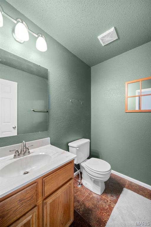 14 Sunderland Ct, Saint Charles, MO 63303 - half bathroom with toilet, a textured ceiling, vanity, tile patterned flooring, and baseboards