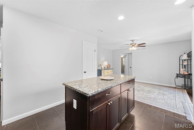 207 Straightoak, Ballwin, MO 63021 - kitchen with a ceiling fan, a textured ceiling, dark tile patterned floors, dark brown cabinetry, and baseboards