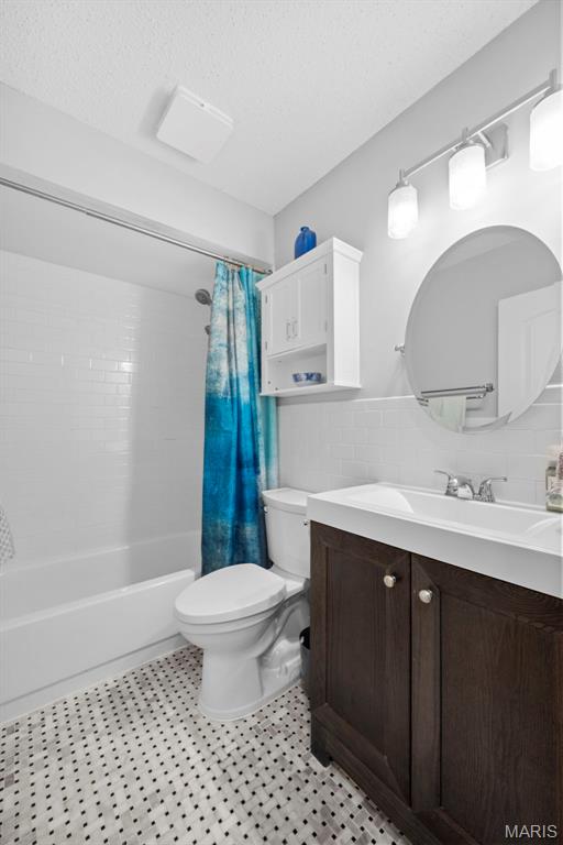 207 Straightoak, Ballwin, MO 63021 - full bathroom with toilet, shower / bath combination with curtain, vanity, tile walls, and wainscoting
