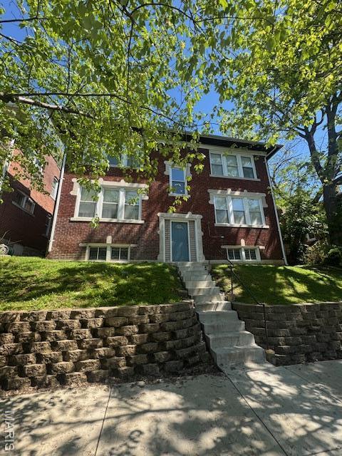view of front of house featuring brick siding and a front lawn