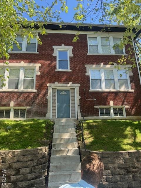 view of front facade featuring brick siding and a front yard