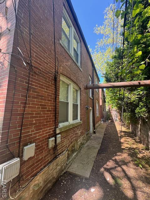 view of side of property featuring brick siding and fence