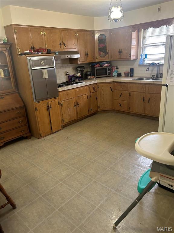 kitchen featuring oven, a sink, gas stovetop, decorative backsplash, and tile counters