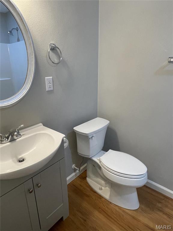 bathroom with wood finished floors, vanity, toilet, and baseboards