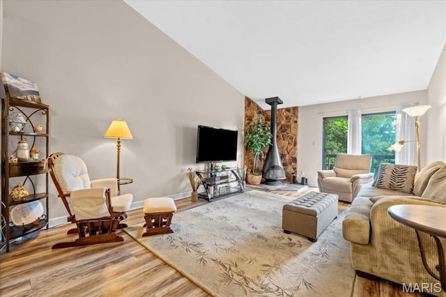 living room with a wood stove, wood finished floors, baseboards, and high vaulted ceiling