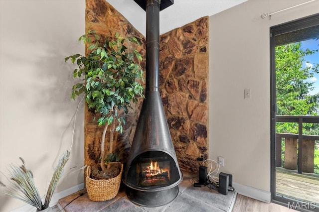 detailed view of a wood stove, baseboards, and wood finished floors