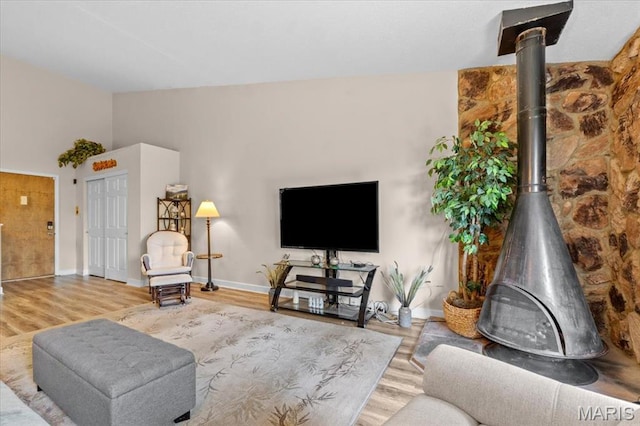 living room featuring a wood stove, wood finished floors, and baseboards