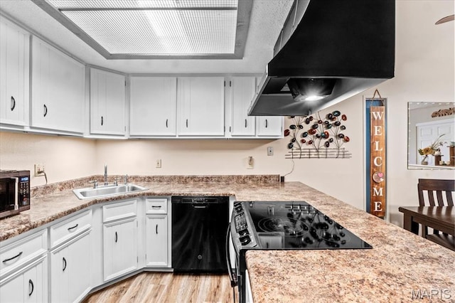 kitchen featuring black appliances, a sink, ventilation hood, light countertops, and light wood-style floors