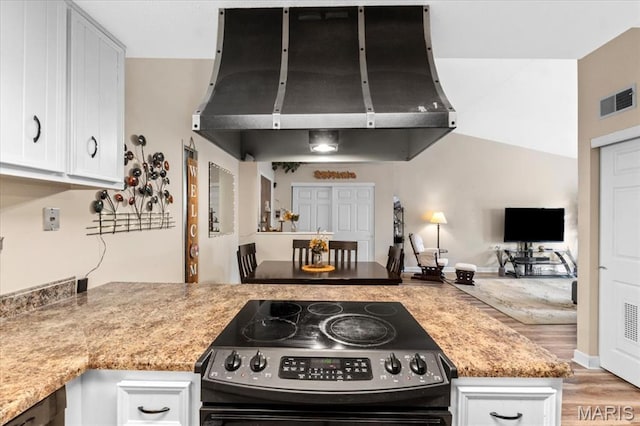kitchen featuring stainless steel range with electric stovetop, exhaust hood, white cabinets, and light wood-style floors