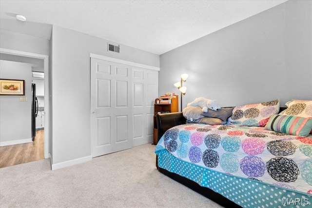 carpeted bedroom with a closet, baseboards, and freestanding refrigerator