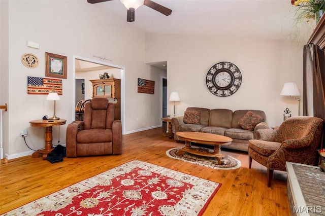 living room with baseboards, a ceiling fan, wood finished floors, and high vaulted ceiling