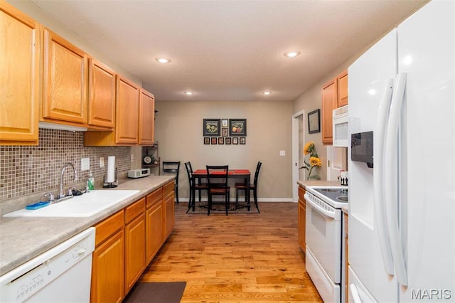 kitchen with white appliances, light wood-style floors, recessed lighting, a sink, and decorative backsplash
