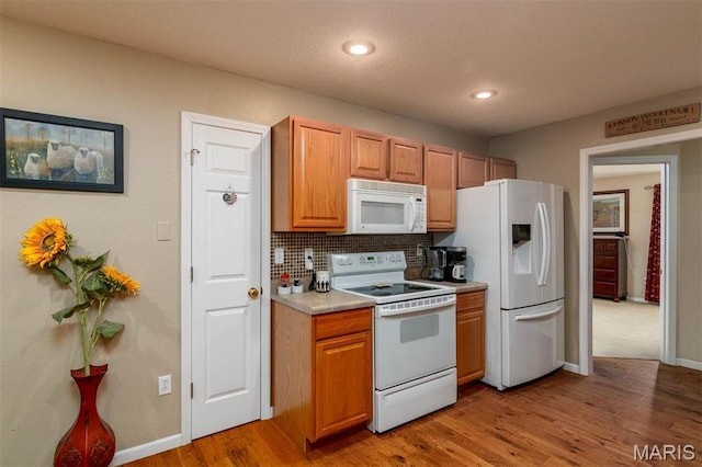 kitchen with white appliances, light wood-style floors, backsplash, light countertops, and baseboards