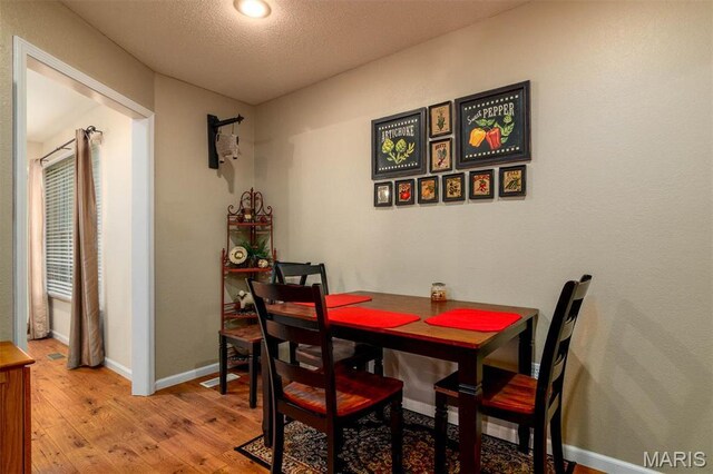 dining area with wood-type flooring, baseboards, and a textured ceiling