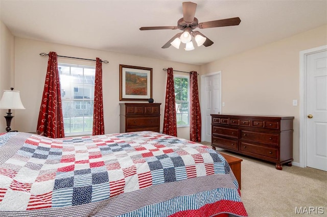 bedroom featuring multiple windows, light colored carpet, and a ceiling fan