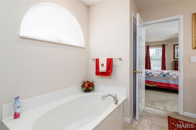 bathroom with connected bathroom, a bath, tile patterned floors, and baseboards