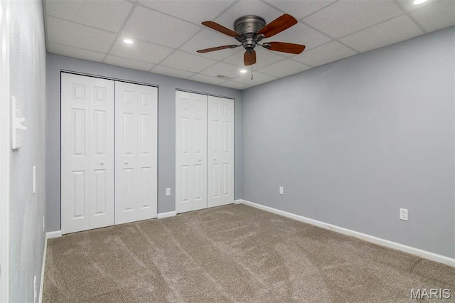 unfurnished bedroom with carpet flooring, multiple closets, baseboards, recessed lighting, and a paneled ceiling