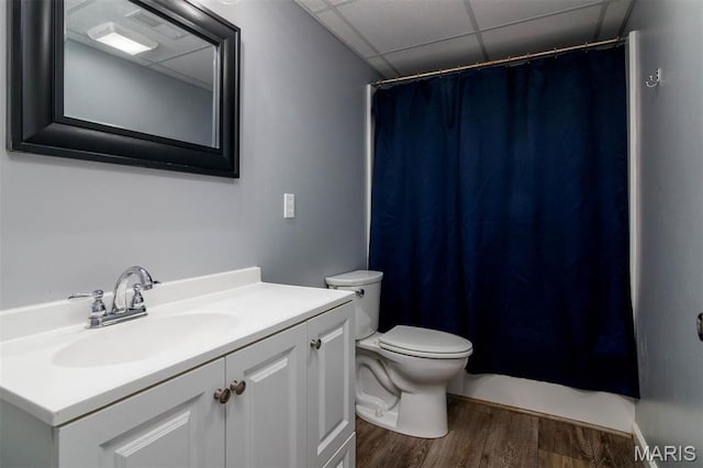 bathroom featuring wood finished floors, a drop ceiling, toilet, vanity, and curtained shower