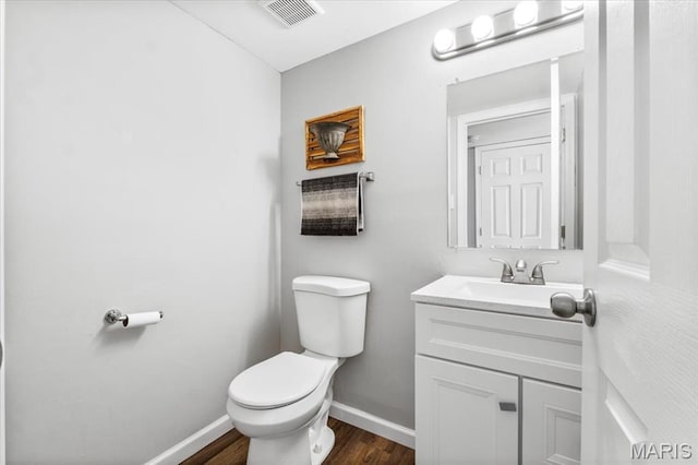 bathroom with baseboards, wood finished floors, toilet, and vanity