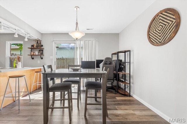 dining space with wood finished floors, plenty of natural light, and baseboards