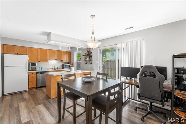 dining area featuring dark wood-type flooring, track lighting, and an office area