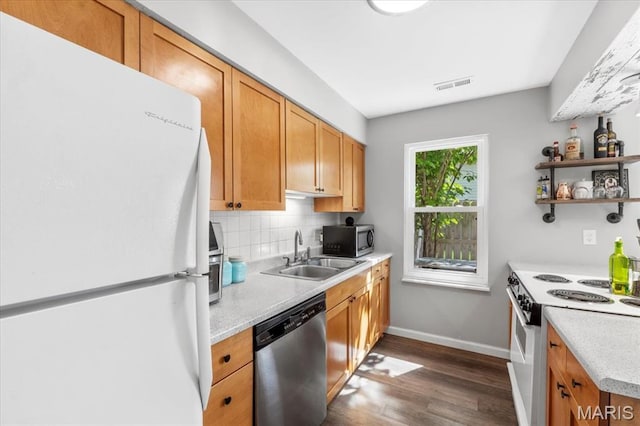 kitchen with appliances with stainless steel finishes, a sink, dark wood-style flooring, light countertops, and baseboards