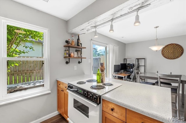 kitchen featuring white electric range oven, light countertops, track lighting, and brown cabinets