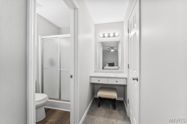 bathroom with connected bathroom, a shower stall, toilet, and baseboards
