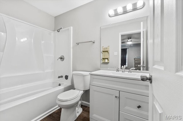 bathroom featuring toilet, wood finished floors, vanity, and tub / shower combination