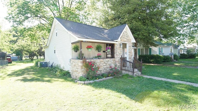 811 N Catalpa St, Dexter, MO 63841 - view of front of property featuring stone siding, a front lawn, a shingled roof, and cooling unit