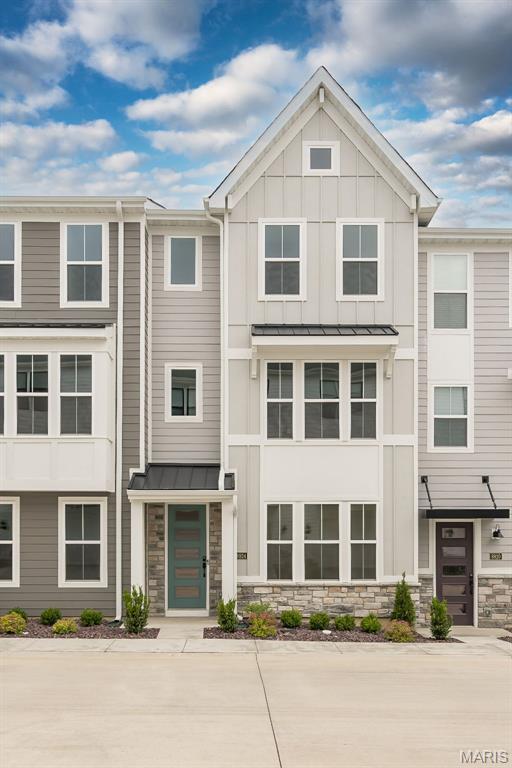 townhome / multi-family property with a standing seam roof, stone siding, board and batten siding, and metal roof