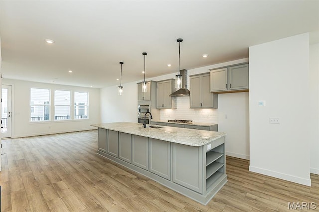 kitchen with gray cabinets, stainless steel gas stovetop, wall chimney range hood, open shelves, and backsplash