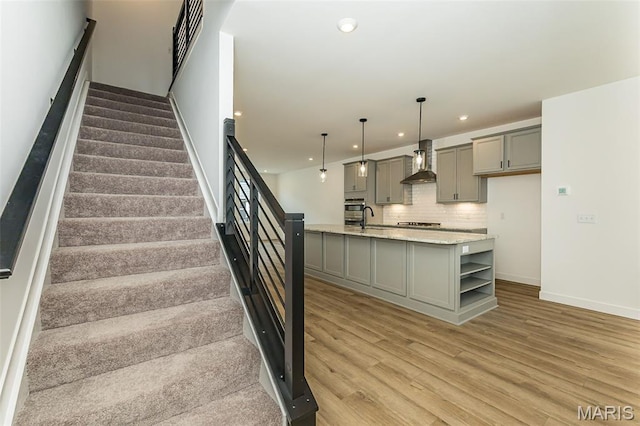 stairs with wood finished floors, recessed lighting, and baseboards