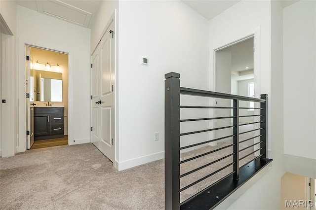 corridor featuring carpet floors, baseboards, and a sink