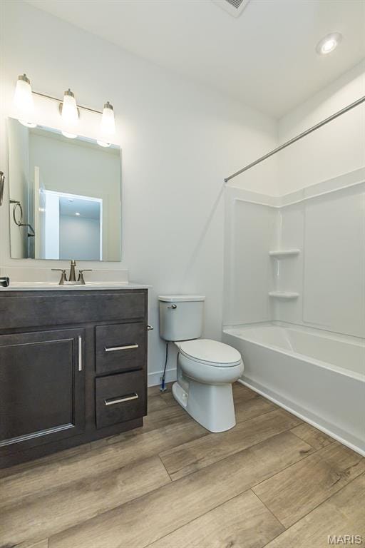 bathroom with toilet, wood finished floors, vanity, shower / tub combination, and recessed lighting