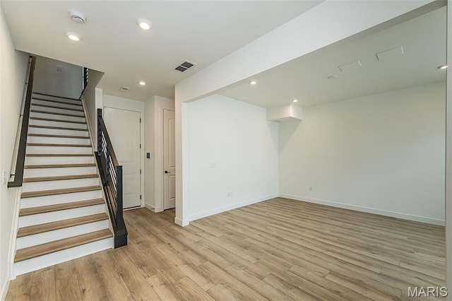 basement featuring light wood-style floors, stairway, baseboards, and recessed lighting