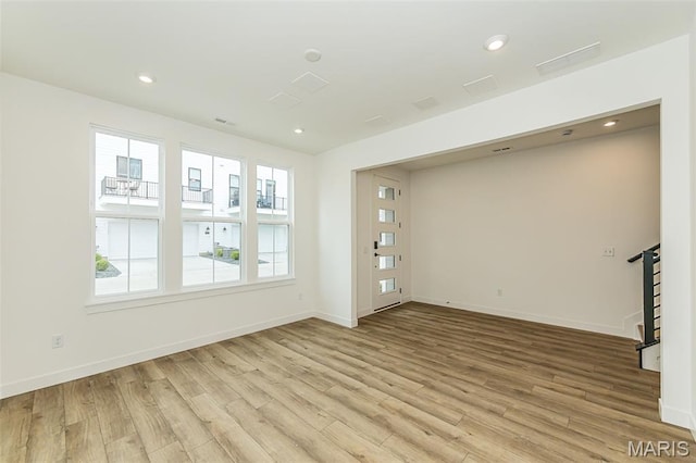 unfurnished living room featuring light wood finished floors, stairway, baseboards, and recessed lighting
