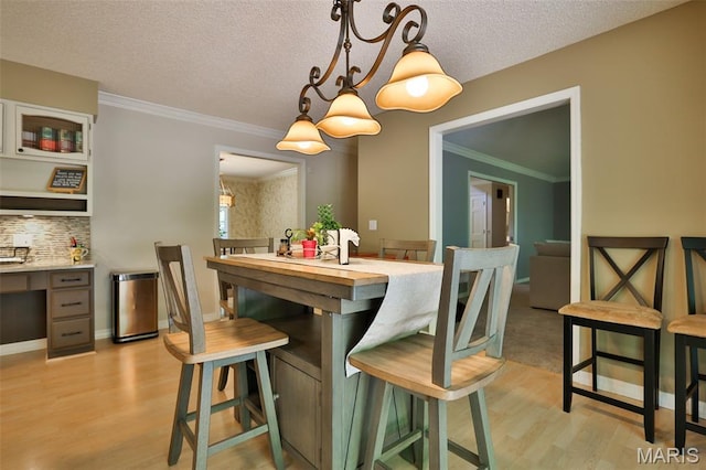 1989 Dogwood Trl, Collinsville, IL 62234 - dining space with light wood finished floors, a chandelier, a textured ceiling, ornamental molding, and baseboards